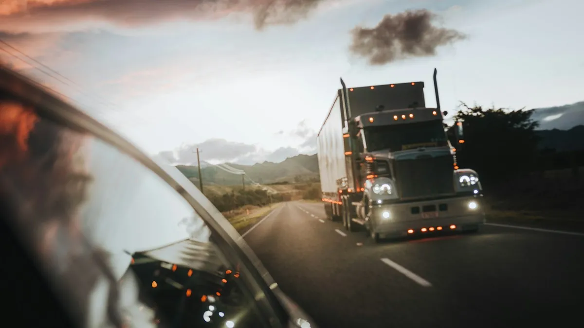 Semi-truck on a highway at dusk, seen from a following car